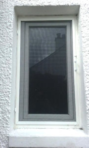 A white fly screen with handle installed externally on a window