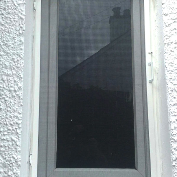 A white fly screen with handle installed externally on a window