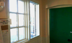 A white screen and sub frame on a window next to a green door