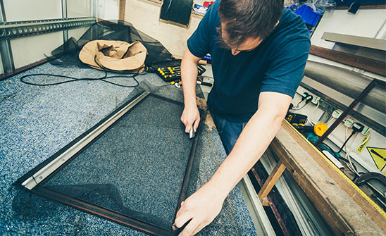 A technician preparing a screen for a window installation