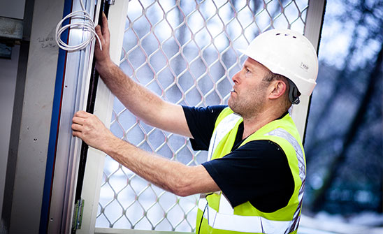 A technician fitting a fly screen window