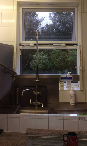 White flexicon screen installed to window in kitchen with high tap in the way