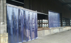 Sliding plastic curtain to warehouse with beer kegs in