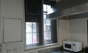 A white sliding fly screen window in a commercial kitchen next to a microwave