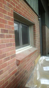 External image of a fly screen installed to a window with a brick building
