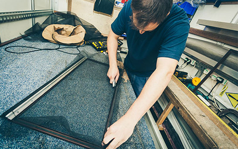 Technician cutting the mesh to fit the window screen